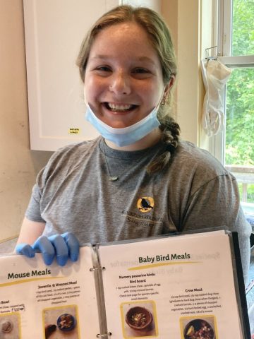 An RWS intern with a cookbook of meals for the animals